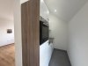 In einer neuen Wohnung steht eine moderne Küche mit einer Wand und einem Ofen. Der Raum ist hell und minimalistisch gestaltet.