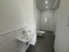 Das Badezimmer zeigt ein Waschbecken und eine Dusche in einem modernen Raum. Es ist hell und gut gestaltet.