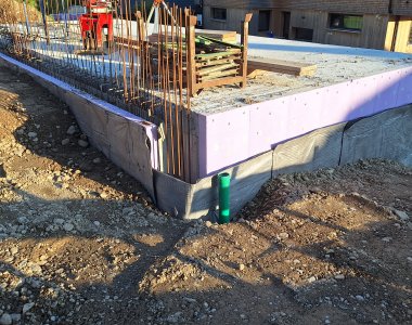 Der Bauarbeiter arbeitet an einem Fundament mit Dammisolierung in einem Baugebiet bei Tageslicht.