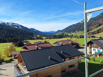 Die Landschaft zeigt ein ruhiges Dorf mit Bergen im Hintergrund an einem klaren Herbsttag.