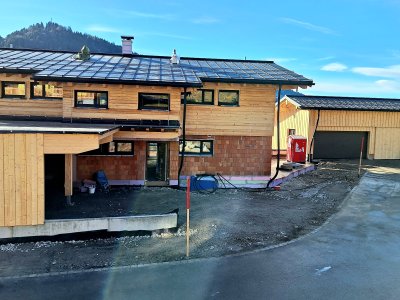 Ein neues Holzhaus entsteht in einer ländlichen Gegend. Der Bau ist fast abgeschlossen und die Umgebung ist klar.