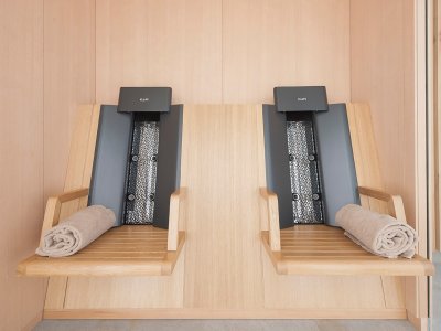Zwei Liegen stehen in einem ruhigen Spa-Raum mit Holzwänden. Die Handtücher liegen bereit für die Gäste.
