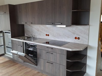 Eine neue Küche wird installiert. Die Holzfronten sind frisch und die Geräte sind in die Einbauschränke integriert.