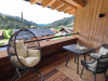 Loggia in Suite Die Sieben Auf dem Balkon stehen ein Tisch und zwei Stühle. Ein Hängesessel ist bereit zum Entspannen. Die Berge sind im Hintergrund sichtbar.