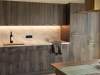 Moderne Küche in Suite SIEBEN In einem Raum mit Holzschränken und Steinarbeiten stehen Flasche und Gläser auf der Arbeitsfläche in der Küche.