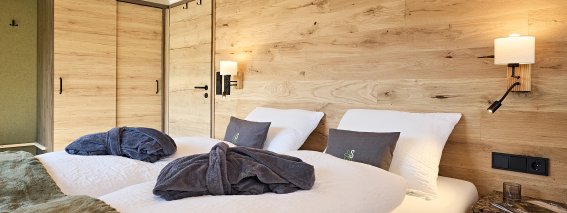 Schlafzimmer mit zwei Betten und Holzdekor In einem modernen Schlafzimmer stehen zwei Betten mit weißen Bettwäsche. Die Wände sind aus Holz.