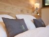 Gemütliches Schlafzimmer mit Kissen und Holz In einem Schlafzimmer liegen zwei Kissen auf einem Bett. Die Wände sind aus Holz und es gibt sanftes Licht.