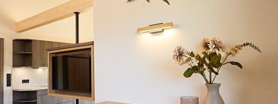 In einem Wohnraum mit Möbeln und Bergmotiven Der Wohnraum zeigt eine stilvolle Einrichtung mit Holzregalen. An der Wand sind Bergmotive zu sehen.