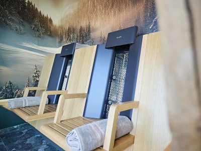 Zwei Holzliegen stehen in einem Wellnessbereich mit Bergblick. Die Atmosphäre ist ruhig und einladend zum Entspannen.