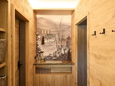 Im Raum stehen Holzregale, ein kleiner Wasserspender und eine Berglandschaft ist an der Wand. Es ist hell und gemütlich.