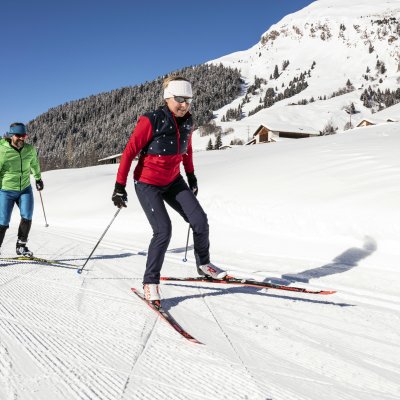 Zwei Freunde genießen einen sonnigen Tag beim Skilanglauf in den Bergen. Die Winterlandschaft ist atemberaubend.