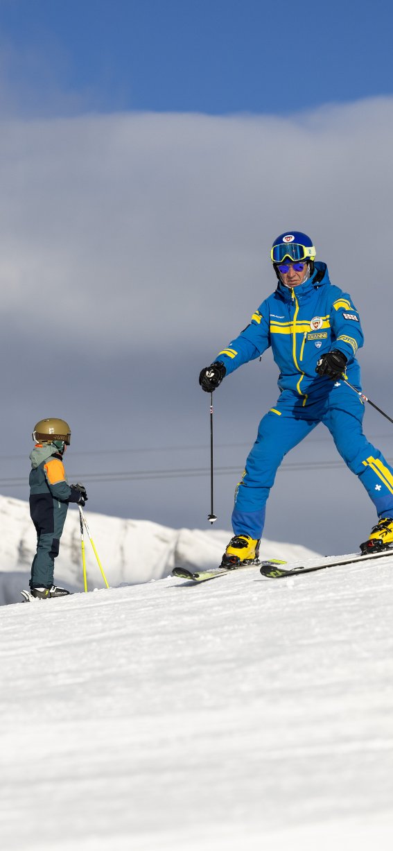 Eine Gruppe von Skifahrern geniesst einen sonnigen Tag in den Bergen. Kinder lernen Ski fahren mit einem Lehrer.