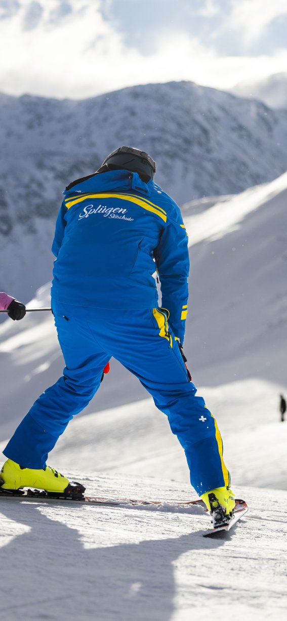 Ein Skilehrer zeigt einem kleinen Mädchen das Skifahren in den Bergen an einem sonnigen Tag.