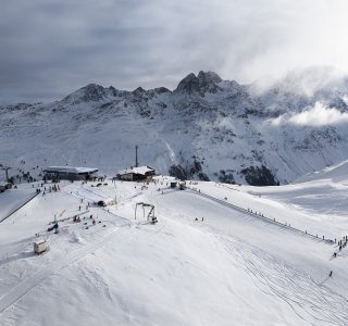 Skifahrer genießen die verschneite Landschaft in den Bergen an einem kalten Wintertag. Die Berge sind majestätisch und bedeckt.