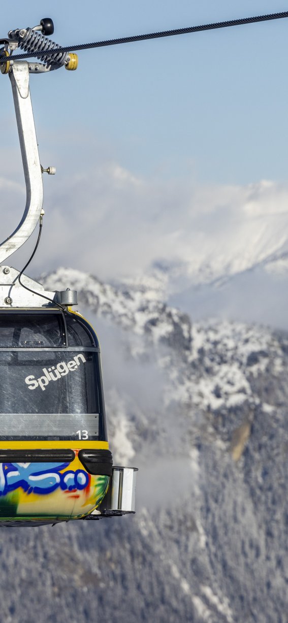 Eine farbenfrohe Bergbahn schwebt über schneebedeckte Berge und bietet einen wunderschönen Blick auf die alpine Landschaft.