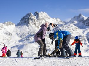 Eine Gruppe von Kindern übt das Skifahren in einem schönen, schneebedeckten Gebirgsgelände.