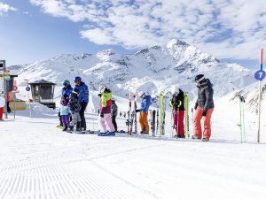 Skifahrer stehen in einer Reihe auf der Piste und bereiten sich auf die Abfahrt in den Bergen vor.
