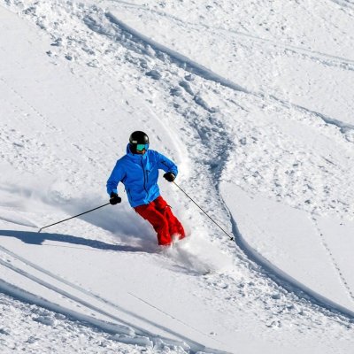 Ein Skifahrer genießt die Piste mit frischem Schnee an einem sonnigen Wintertag in den Bergen.