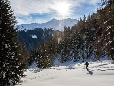 Ein abenteuerlustiger Wanderer bewegt sich durch verschneite Landschaften im Gebirge an einem sonnigen Wintertag.