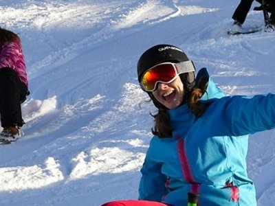 Gruppe von Freunden genießt einen sonnigen Wintertag beim Schlittenfahren in den Bergen.