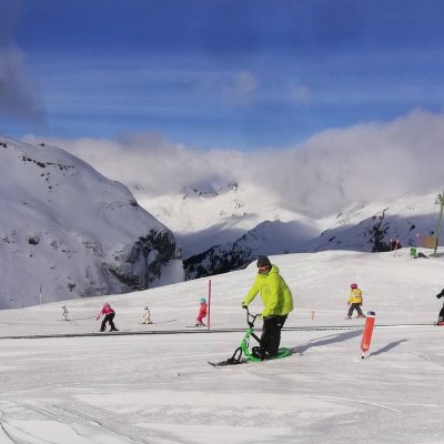 Mehrere Personen genießen das Skifahren im Schnee der Alpen an einem sonnigen Wintertag.