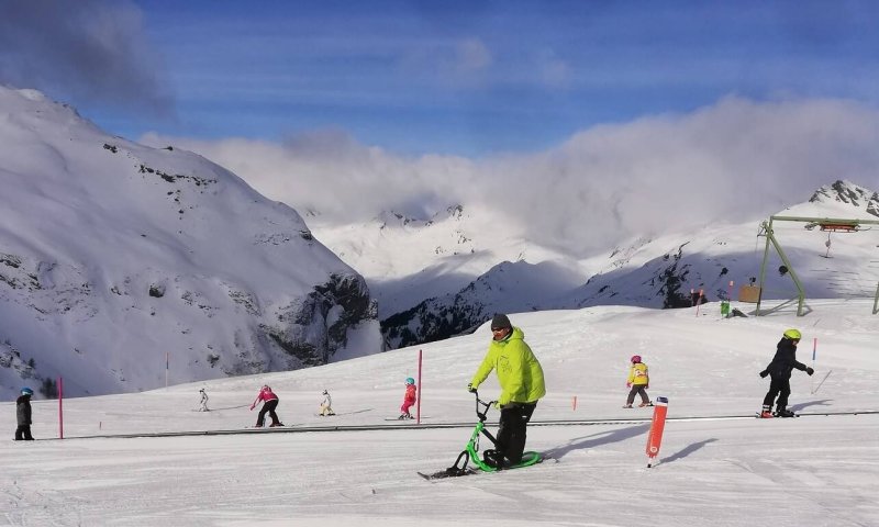 Mehrere Personen genießen das Skifahren im Schnee der Alpen an einem sonnigen Wintertag.