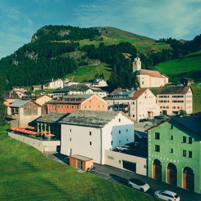 Das Dorf zeigt die Spleuca, Berge und einen klaren Himmel. Menschen verbringen Zeit draußen in einer schönen Umgebung.