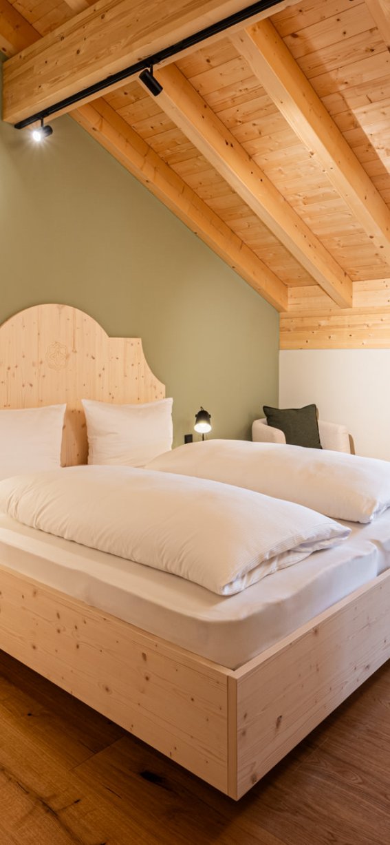 Dieses freundliche Zimmer im Dachgeschoss hat Holzdetails, ein großes Bett und viel Tageslicht durch das Fenster.