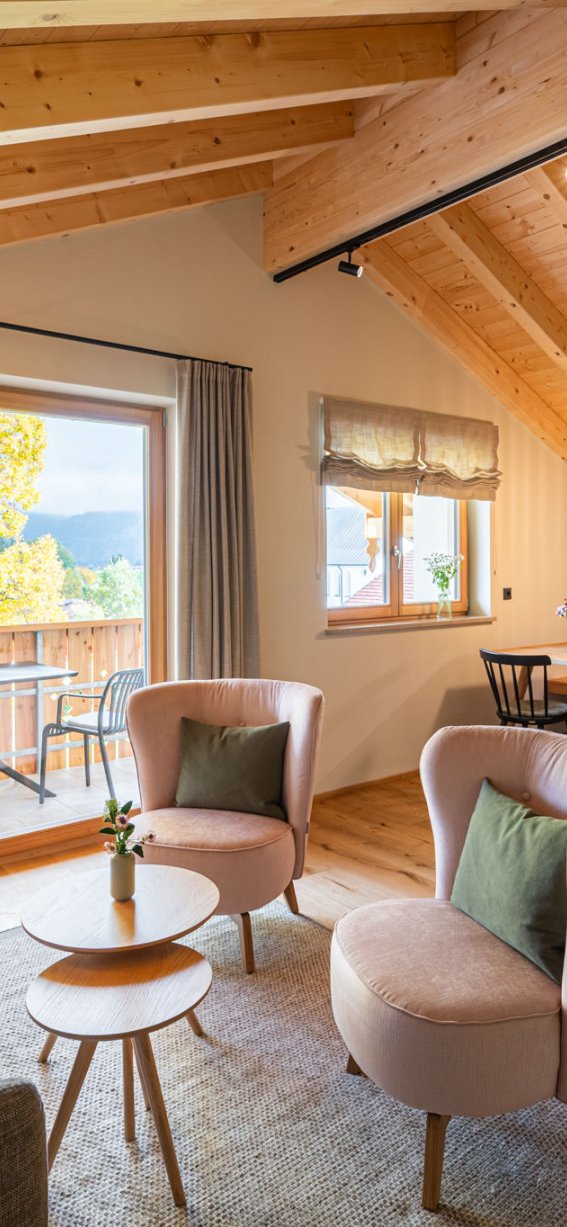 Gemütliches Zimmer mit Holzbalken, modernen Möbeln und Blick auf die Berge. Ideal für entspannte Nächte und gesellige Stunden.