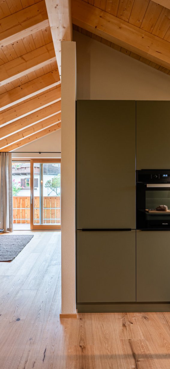 In einer hellen und modernen Wohnung mit Holzdecken wird gekocht und entspannt. Der Raum bietet eine gemütliche Atmosphäre.