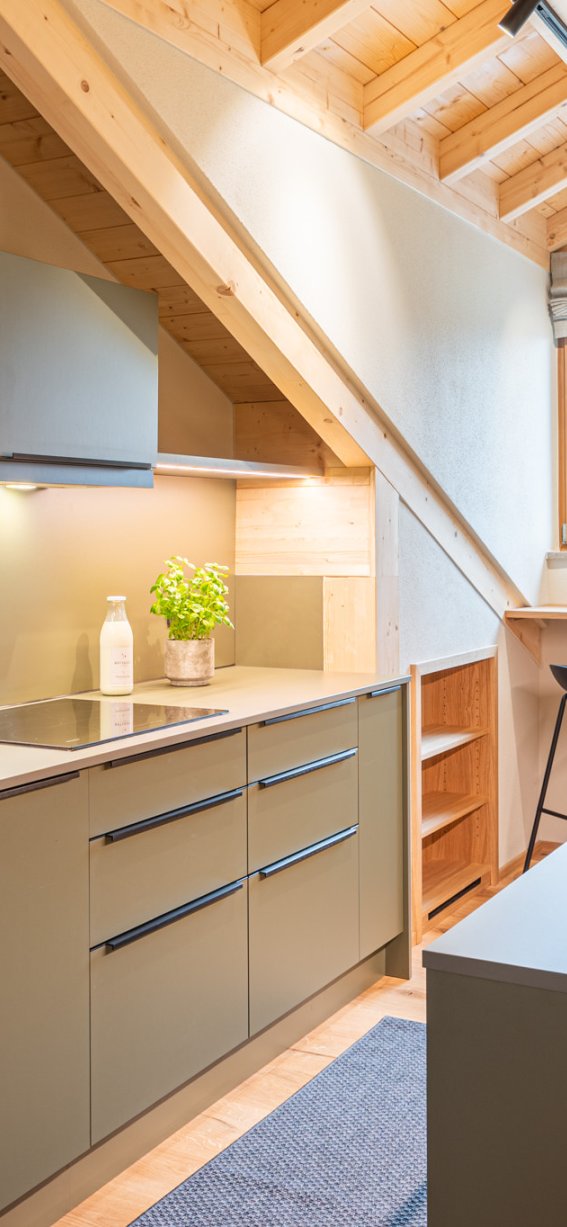 Eine gut ausgestattete Küche mit Holzdecke und großen Fenstern. Ideal für das Kochen und gesellige Zusammenkünfte.