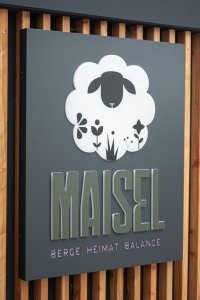Die einladende Fassade von Maisel zeigt eine Schafskulptur und betont den Fokus auf Natur und Balance in den Bergen.