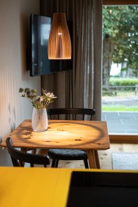 In einem modernen Wohnzimmer stehen ein Esstisch und eine gemütliche Couch. Der Blick durch das große Fenster zeigt einen schönen Garten.