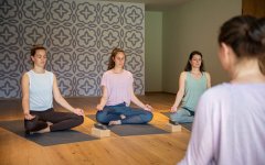 Vier Frauen meditieren in einem ruhigen Yogaraum mit sanfter Beleuchtung und entspannender Atmosphäre.