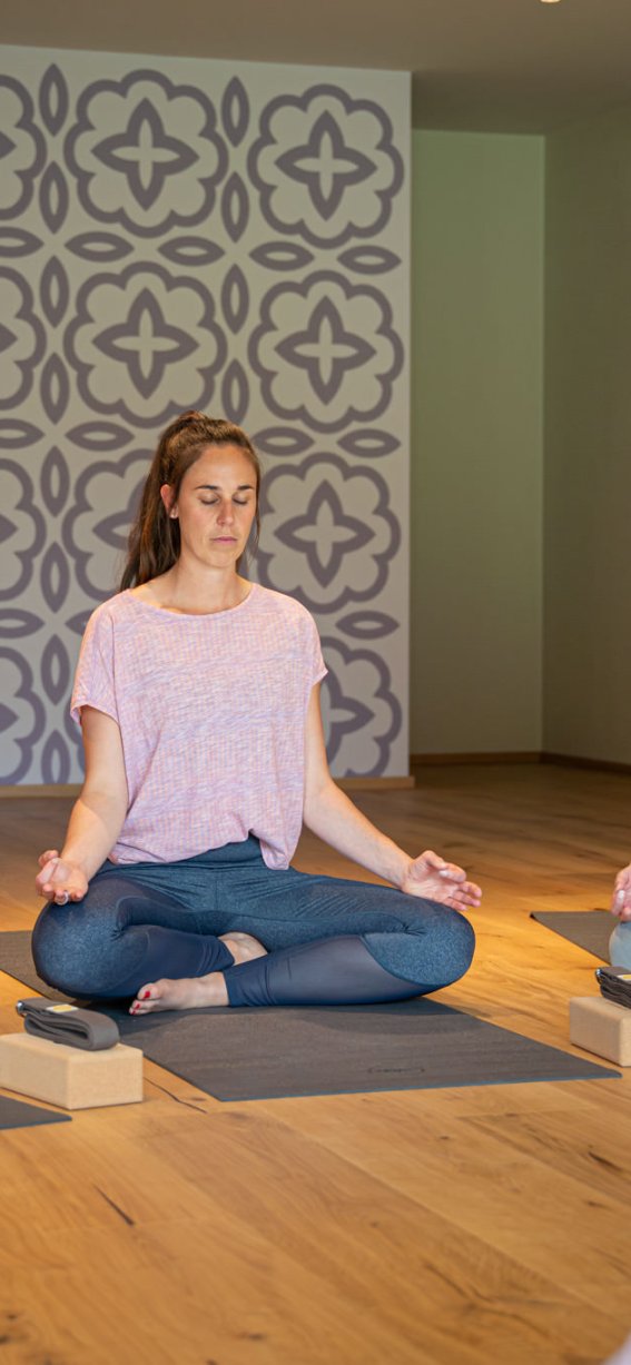 Vier Frauen meditieren in einem ruhigen Yogaraum mit sanfter Beleuchtung und entspannender Atmosphäre.