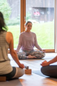 Frauen praktizieren Meditation in einem hellen Raum. Sie konzentrieren sich auf ihre Atmung und genießen die Ruhe.