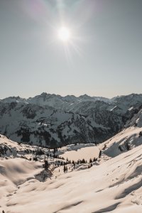 Weite, schneebedeckte Berge unter einem klaren Himmel an einem sonnigen Wintertag.