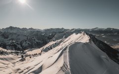 Eine atemberaubende Aussicht auf schneebedeckte Gipfel. Die Sonne scheint hell über die alpine Landschaft.