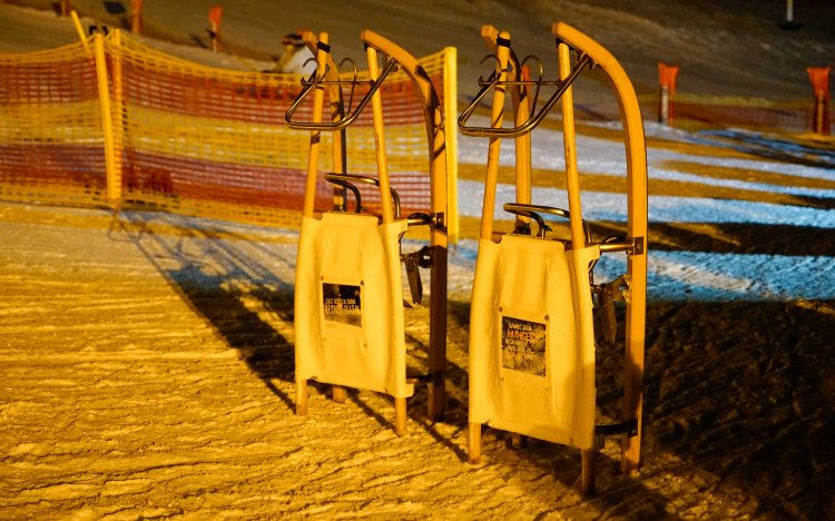 Zwei Holzschlitten stehen bereit, um in der Nacht auf gut präparierten Pisten zu fahren und Spaß zu haben.