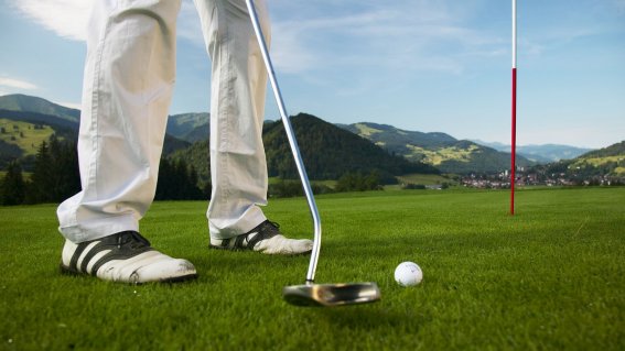 Nahaufnahme eines Golfers mit den Allgäuer Bergen im Hintergrund