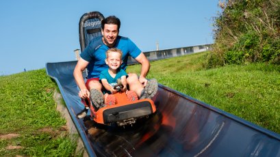 Papa mit Sohn geben Gas auf der Sommerrodelbahn am Hündle
