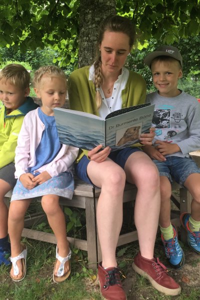 Roman, Annelie und Clemens freuen sich mit Erzieherin Johanna Kleiner vom Kindergarten St. Martin über das neue Vorlesebuch.