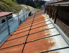 Handwerker sanieren das Blechdach der Walserschanz an einem sonnigen Tag.