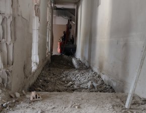 Im Flur eines Hauses finden Renovierungsarbeiten statt. Der Boden ist aufgerissen und Materialien liegen verstreut.