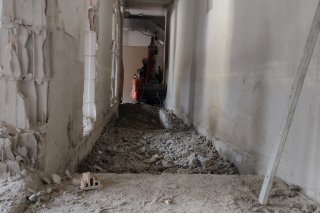 Sanierungsarbeiten Kellergeschoss Im Flur eines Hauses finden Renovierungsarbeiten statt. Der Boden ist aufgerissen und Materialien liegen verstreut.