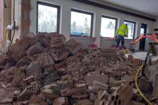 Renovierungsarbeiten mit Abbruchmaterial in einem Raum. Die Fenster lassen Licht hinein.