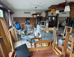 Im Raum arbeiten mehrere Personen. Sie reparieren Fenster und benutzen verschiedene Werkzeuge. Es ist tagsüber.