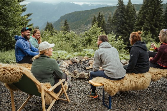 Das Knistern der Flammen und der Duft von brennendem Holz schaffen eine gemütliche Atmosphäre auf der Wannenkopfhütte. Die Sitzplätze rund um das Lagerfeuer sind mit Decken und Kissen ausgestattet, damit es auch bei kühleren Abendtemperaturen wohlig warm bleibt.
