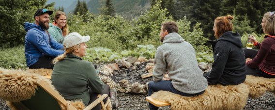 Das Knistern der Flammen und der Duft von brennendem Holz schaffen eine gemütliche Atmosphäre auf der Wannenkopfhütte. Die Sitzplätze rund um das Lagerfeuer sind mit Decken und Kissen ausgestattet, damit es auch bei kühleren Abendtemperaturen wohlig warm bleibt.
