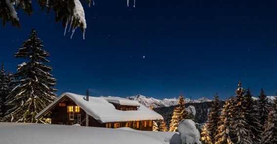 WH Winter Außenansicht Markus Trienke Eine Außenansicht der verschneiten, beleuchteten Wannenkopfhütte bei Nacht.